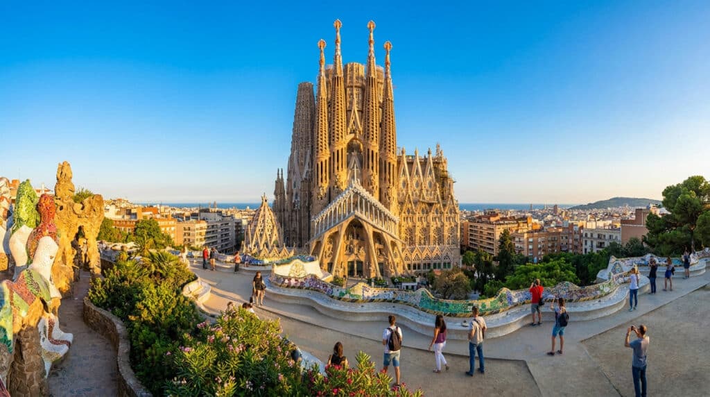 Vue panoramique de la Sagrada Família avec les touristes au Parc Güell sous un ciel bleu éclatant.